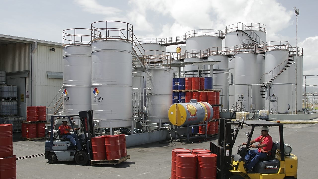 Dos montacargas transportan cuatro barriles rojos cada uno, en la planta de Lubricantes Shell en Valencia - Venezuela.