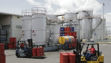 Dos montacargas transportan cuatro barriles rojos cada uno, en la planta de Lubricantes Shell en Valencia - Venezuela.