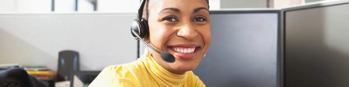 Mujer con camisa amarilla sentada sonriendo con sus auriculares puestos