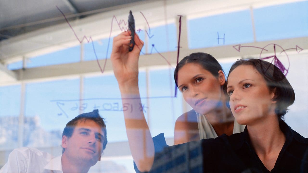 Mujer de negocios dibujando gráficos en una pizarra transparente
