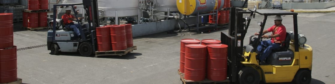 Dos montacargas transportan cuatro barriles rojos cada uno, en la planta de Lubricantes Shell en Valencia - Venezuela.