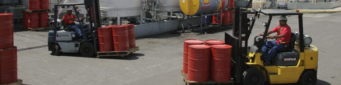 Dos montacargas transportan cuatro barriles rojos cada uno, en la planta de Lubricantes Shell en Valencia - Venezuela.