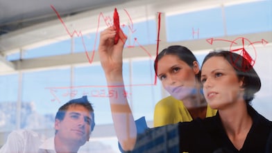 Mujer de negocios dibujando gráficos en una pizarra transparente