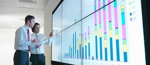 Hombres de negocios analizan informes visualizados en una gran pantalla digital