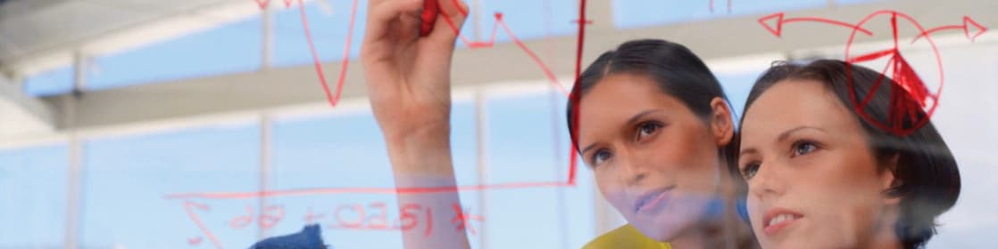 Mujer de negocios dibujando gráficos en una pizarra transparente