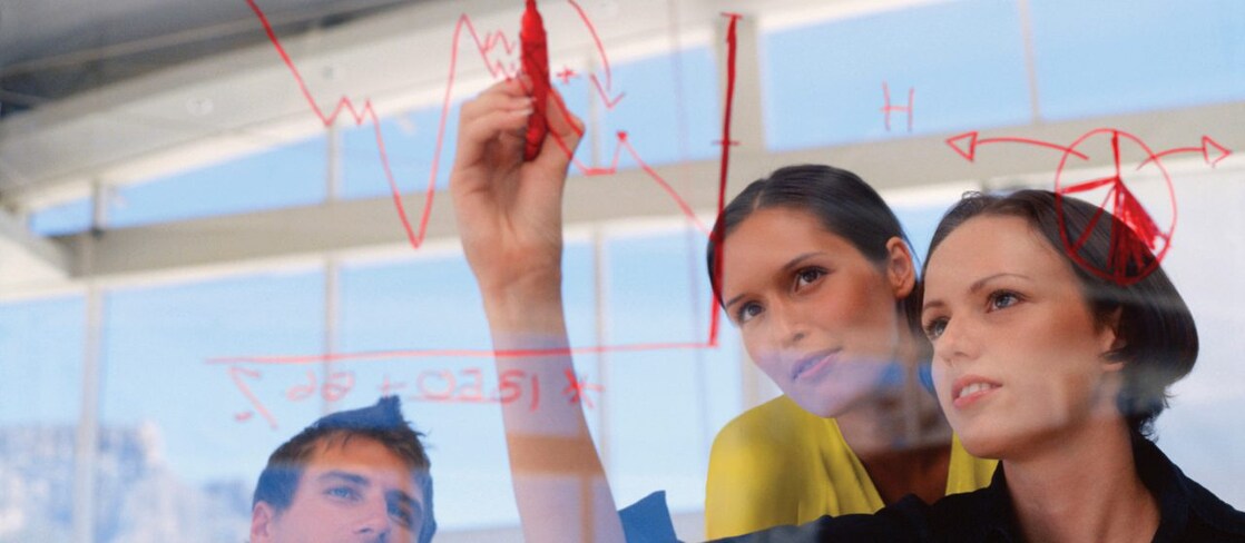 Mujer de negocios dibujando gráficos en una pizarra transparente