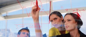 Mujer de negocios dibujando gráficos en una pizarra transparente